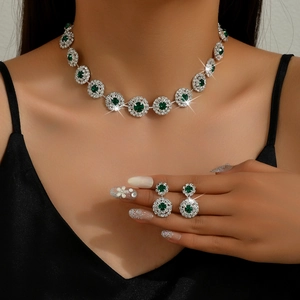 Detalle de set de joyas para novia con diamantes de imitación verde esmeralda y halo