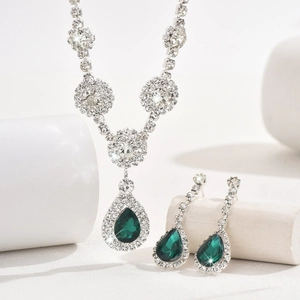 Macro detail of emerald pear-cut gemstone jewelry set with silver necklace and earrings
