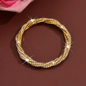 Macro shot of gold-plated multi-layer twisted bracelet with sparkling rhinestones details