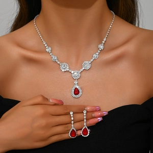 Close-up of sparkling zircon jewelry set with pear-shaped ruby red stones on a model