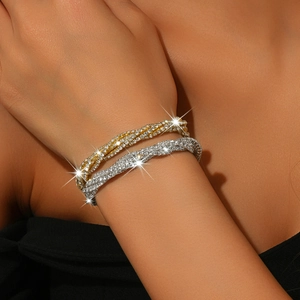 Detail of twisted gold and silver bracelets set with sparkling rhinestones on wrist