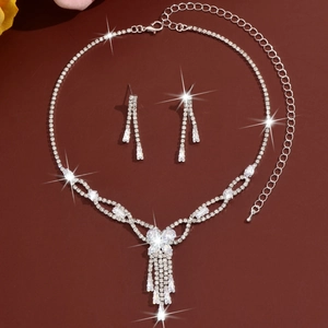 Detailed view of silver necklace and earrings set with crystal tassels and bow design