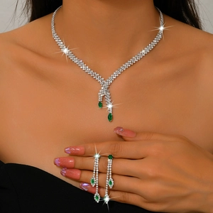 Detalle de lujoso conjunto de joyas de circonita verde esmeralda con collar y pendientes largos