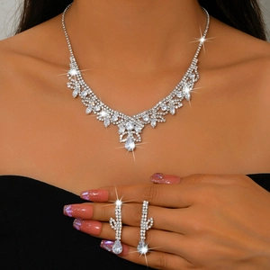 Gros plan sur parure de mariée avec collier en V et boucles d'oreilles goutte en strass