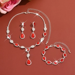Detailed view of silver necklace and earrings set with red pear-cut gems and crystals
