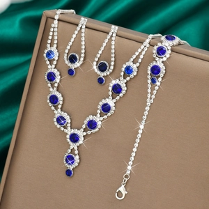 Detailed view of luxury silver-toned jewelry set with deep blue crystals on green silk