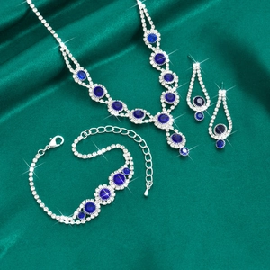 Detail of luxury bridal jewelry set with blue rhinestones on green satin background