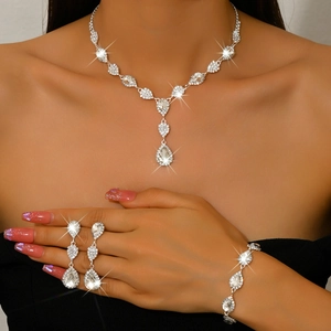 Close-up of silver bridal jewelry set with pear-cut crystals on model in black dress