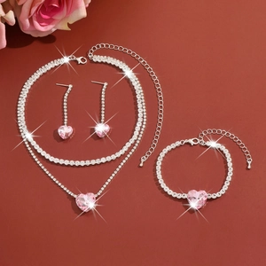 Flat lay of jewelry set with pink heart crystals and silver metal on dark background