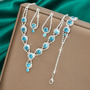 Macro shot of silver jewelry set with sea blue stones and diamonds on silk background