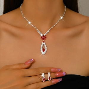 Detail of elegant teardrop necklace and earrings set with ruby red resin and crystals
