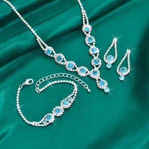 Detailed view of silver necklace bracelet and earrings set with blue crystals on silk