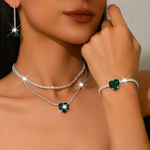 Elegant silver jewelry set with emerald green heart stones on a necklace and bracelet