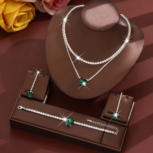 Macro view of four-piece jewelry set with green heart emeralds and silver chain