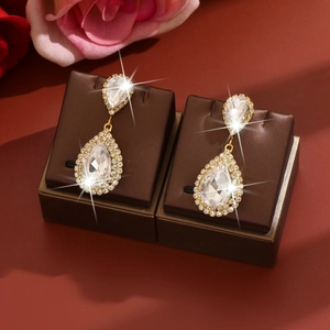 Detalle de pendientes dorados en forma de gota con cristales brillantes para novia