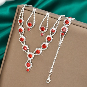 Detailed view of silver jewelry set with red rhinestones and clear zircon on silk