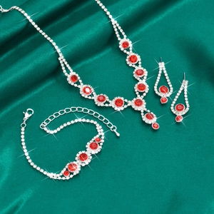 Macro shot of bridal jewelry set with red ruby crystals on green silk fabric backdrop