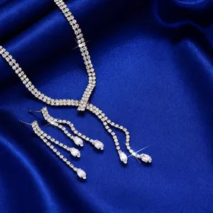 Macro detail of silver necklace and earring set with shimmering tassels on dark blue silk
