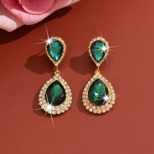 Detalle de pendientes de novia con gemas verdes en forma de gota y cristales finos