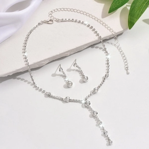 Silver jewelry set with Y-shaped necklace and drop earrings on white silk and marble