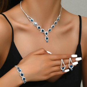 Close-up of elegant silver necklace, bracelet, and earrings set with deep blue rhinestones