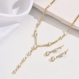 Close-up of gold-plated necklace and drop earrings set with shimmering white zircons