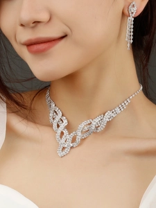 Dettaglio del set sposa con collana a V e orecchini pendenti ricoperti di strass lucenti