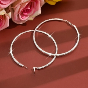 Detailed close-up of sparkling silver hoop earrings with full rhinestone inlay design
