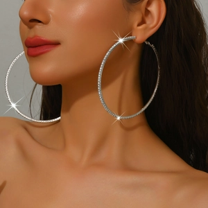 Close-up of oversized silver hoop earrings with sparkling rhinestones worn by a model