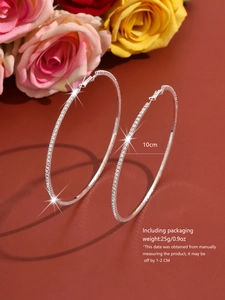 Detailed view of 10cm oversized silver hoop earrings with glittering white crystals