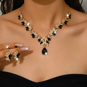 Close-up of golden leaf necklace and earrings set with black teardrop crystals