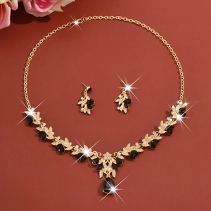 Detailed view of elegant gold necklace and earring set with black teardrop gems