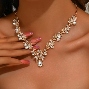 Detailed close-up of a glittering gold flower necklace with a large teardrop crystal