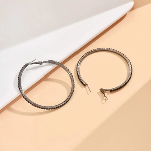 Macro shot of 80mm gunmetal grey hoop earrings with black rhinestones on a warm background