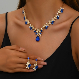 Close-up of bridal jewelry set with navy blue teardrop gems and gold vine patterns