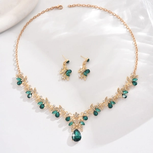 Detail of bridal jewelry set with emerald green crystals and vine leaf gold finish