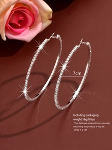 Macro shot of 7cm silver hoop earrings with sparkling rhinestones and size details