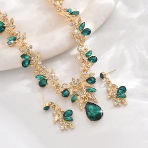 Detail of gold bridal jewelry set with emerald green waterdrop stones and leaf motifs
