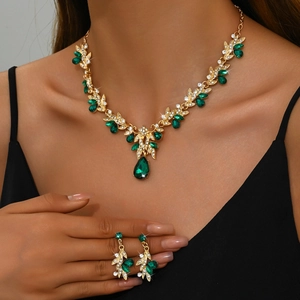 Detail view of luxurious bridal jewelry set with emerald green crystals and gold leaves