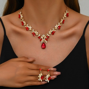 Detailed view of bridal jewelry set with gold leaf design and red pear-shaped rhinestones