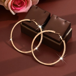 Detailed view of large rose gold hoop earrings with white zircon on jewelry boxes