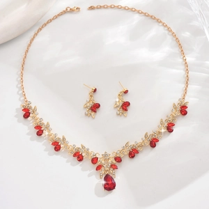 Close-up of elegant gold bridal jewelry set with ruby red water-drop crystals