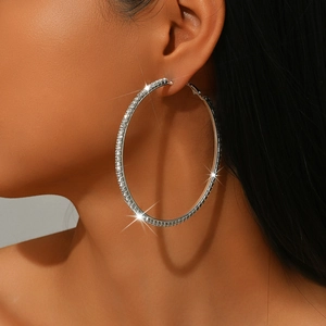 Detail shot of large silver hoop earrings with shimmering rhinestones on a model