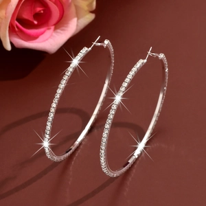 Detailed view of silver hoop earrings with shimmering rhinestones on a dark background