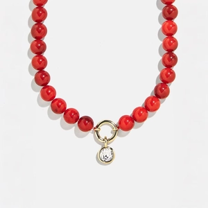 Detail of red beaded necklace with golden clasp and clear crystal pendant