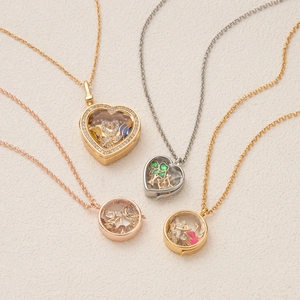 Vintage locket pendant necklaces with glass locket and miniature love charms on beige texture
