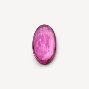 Detailed macro view of an oval-cut faceted pink gemstone with deep color and high clarity