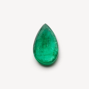 Macro shot of a pear-shaped emerald gemstone with vibrant green color on white background