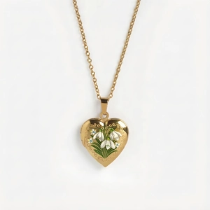 Makro-Detail des goldenen Herz-Medaillons mit weißer Emaille-Blume und Ornament-Rand