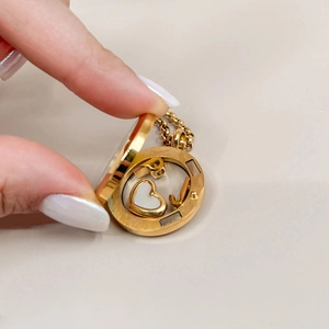 Close-up of gold locket opening to reveal a white heart pendant with fine chain